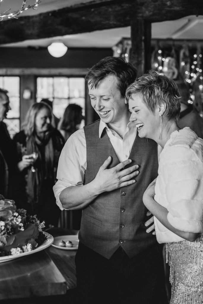 A bride and groom smiling looking at their wedding cake. Wedding planning during COVID-19 | Hope Allison Photography Boston wedding photographer